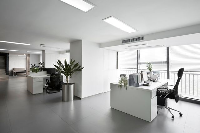 Modern, bright office space with clean white desks and green plants.