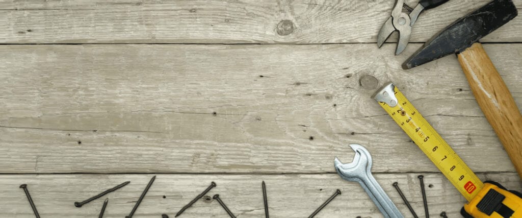 Wrench, nails, and nails on wooden surface.