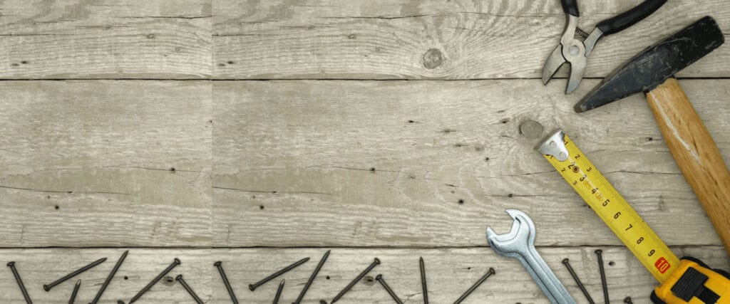 Scattered nails and a crescent wrench on a weathered wooden surface.