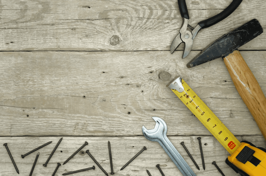 Various hand tools and nails on a wooden surface.