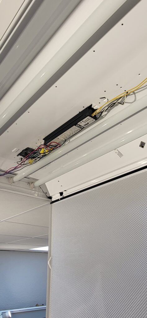 Ceiling-mounted projector with exposed wiring and components.