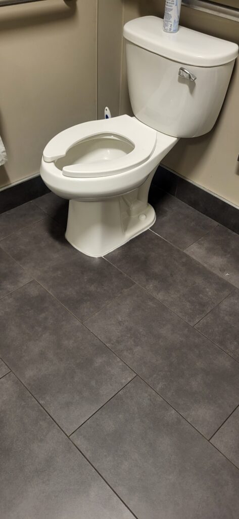 A white toilet installed on a dark tiled floor.