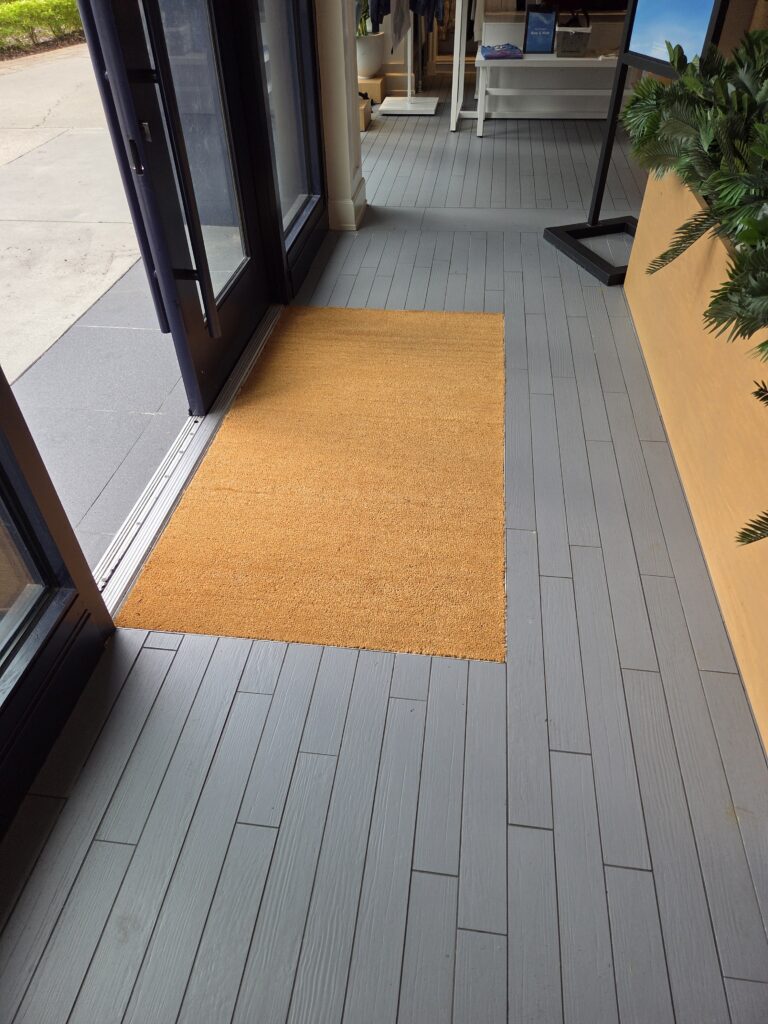 Entrance with a yellow doormat on a gray wooden floor.